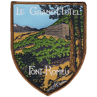 Ecusson brodé souvenir du Grand hôtel de Font-Romeu. Il est en forme de blason pointe vers le bas et reptrésente le grand hôtel et le paysage environnant. 