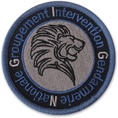 L'écusson rond du GIGN représente en son centre une tête de lion noir sur fond gris. Autour, un bandeau noir sur lequel le texte groupement d'Intervention Gendarmerie Nationale est brodé en bleu.