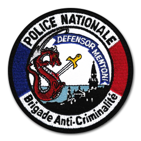 Ecusson rond brodé de la police nationale BAC de Menton. Il représente un paysage noir sur fond de mer bleue. Au dessus, sur la gauche, un dragon rouge transpercé d'une épée. Sur un parchemin bleu, on peut lire le texte Defensor Menton. Le bord de l'écusson est un bandeau bleu blanc rouge sur lequel est brodé le texte police nationale, Brigade anti-criminalités.