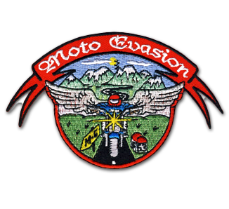 Ecusson du club de moto Moto evasion. il représente un motard de face, sur une moto bleue avec un phare brillant. Sur les côtés du motard, des ailes d'ange grises et dans le fond, un paysage de montagne. Sur le haut de l'écusson, il y a un bandeau rouge type parchemin sur lequel est écrit moto evasion en blanc. L'écusson est découpé à la forme du dessin.