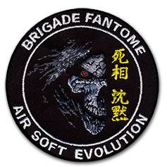 Ecusson rond brodé du club d'airsoft Evolution brigade fantome. Il représente une tête de squelette ou de zomie, en gris avec les yeux rouges, sur un fond noir, dans l'ombre. A droite, des idéogrammes jaunes. Sur le bord de l'écusson, en bas le nom du club et en haut Brigade fantôme en blanc sur fond noir.