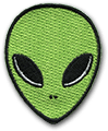 Ecusson brodé découpé à la forme d'une tête d'Alien. La tête est verte, avec les yeux noirs et deux points pour représenter le nez. Le bord de la tête est un fin liserai noir.