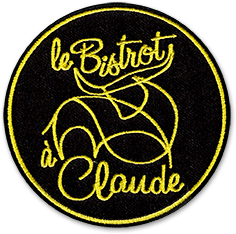 Ecusson brodé représentant le logo du restaurant le Bistrot à Claude. Il est rond, avec un fond noir, sur lequel est brodé en jaune une forme assez fine au centre; autour de laquelle est brodé, toujours en jaune, le texte Le Bistrot à Claude.