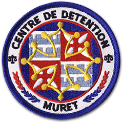 Ecusson brodé du centre de détention de Muret. Brodé en 7 couleurs, il représente la croix occitane au-dessus d'un drapeau.