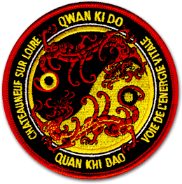 Ecusson rond brodé du club de Qwan Qi Do de Chateauneuf sur loire. Au centre de l'écusson, le symbole de ying et du yang est brodé en jaune et noir. Par dessus, deux silhouettes de dragons rouges et oranges. Le bord de l'écusson est un bandeau noir sur lequel est écrit Qwan Qi Do, voie de l'énergie vitale, Chateauneuf sur loire.