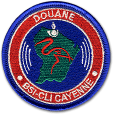 Ecusson rond brodé de la douane de Cayenne. Il représente la carte de la guyane en vert sur fond bleu, surmontée d'une silhouette d'oiseau. Autour, le texte Douane, BSI-CLI Cayenne est écrit en blanc sur fond rouge.