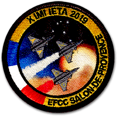 Ecusson brodé et imprimé de forme ronde. Au centre, trois avions type rafale sont en train de voler dans un ciel faisant apparaître des étoiles et une planète. Ils laissent derrière eux des trainées bleu lanc rouge. Autour, un bandeau avec les couleurs du drapeau français et le texte XIMI IETA 2019 EFCCC Salon de Provence