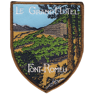 Ecusson brodé en 10 couleurs en forme de blason, représentant le Grand Hôtel de Font-Romeu et le paysage environnant. 