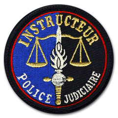 Ecusson rond brodé de la police judiciaire. L'écusson a un fond en deux parties, à gauche du bleu à droite du noir. Au centre, la balance de la justice est brodée, devant laquelle on voit la grenade à huit branches. Le texte Instructeur est brodé en lettres capitales couleur or en haut, en en bas on peut lire police judiciaire.