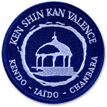 Ecusson de l'école de sabre japonais Ken Shin Kan de Valence. L'écusson rond est brodé en blanc sur fond bleu. Il représente un bâtiment traditionnel au centre, entouré d'un cercle et sous lequel figure le texte Kendo Jaido Chanbara.