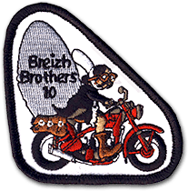 Ecusson brodé découpé du club de moto Breizh Brothers. Il a une forme de triangle et représente une bigoudaine sur une moto rouge. Derrière, un rocher qu'elle transporte sur lequel est écrit Breizh brothers 10.