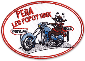 Ecusson brodé du club de moto les Popot'Hinx. L'écusson ovale représente une vache sur une moto bleue, le tout sur fond blanc. La bordure de l'écusson est rouge, tout comme le texte en haut à gauche Pena popot'hinx.