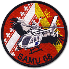 Ecusson brodé du SAMU du haut Rhin. Il est rond et représente un hélicoptère surmonté d'une cigogne sur fond rouge avec un triangle jaune et blanc. il porte l'inscription SAMU 68.