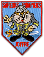 Ecusson brodé des sapeurs-pompiers en forme de blason. Il représente un chat au visage humain, debout sur ses jambes, dans un style BD. Sur fond bleu, le texte Sapeurs-pompiers est écrit en rouge au-dessus du personnage, et Joffre est inscrit en-dessous.
