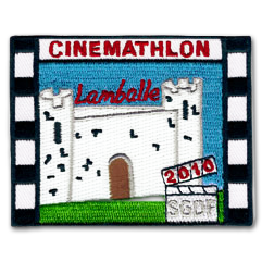 Ecusson brodé des scouts de Lamballe pour l'évènement cinemathlon 2010. L'écusson est rectangulaire et représente un chateau fortifié blanc sur fond de ciel bleu, et devant lequel est brodée une herbe verte. Sur le château, le texte lamballe et la mention 2010. Le contour de l'écusson est une pellicule de cinéma en noir et blanc.