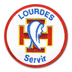 Ecusson rond brodé des scouts de lourdes. Il représente la croix potencée au centre, en rouge et bordure jaune au dessus de lquelle est brodée la silhouette de Marie. Au dessus, le texte lourdes en lettre capitale bleues et dessous, le texte servir.