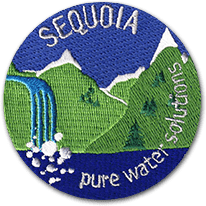 Ecusson brodé de la société Sequoia représentant des montagnes vertes desquelles s'écoule une cascade dans une eau bleue. En bas de l'écusson découpé, le texte pure water solutions.