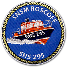 Ecusson brodé rond des sauveteurs en mer de Roscoff. Il représente un bateau rouge et bleu foncé sur la mer. Le tour de l'écusson est une corde de bateau. Sur l'écusson en haut est écrit SNSM Roscoff, et dessous SNS 295.