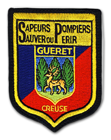 Ecusson brodé des pompiers de Guéret. Il a une forme de blason. En hait, un bandeau couleur or sur lequel est brodé le texte Sapeurs pompiers, ainsi que la devise sauver ou périr. Dessous, un fond avec deux bandes diagonales rouges et bleues sur lesquelles on voit un petit blason représentant un cerf dans une forêt avec le texte GUERET en lettres capitales au dessus. Dessous, le texte creuse est brodé en couleur or.