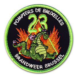 Ecusson brodé rond des pompiers de Bruxelles. Il représente un gentil dragon vert, assis sur ses fesses, devant un triangle vert des des flammes jaillissantes. Au dessus de lui, le chiffre 23 est brodé en vert fluo. En haut, le texte Pompiers de bruxelles et en bas Brandweer Brussel sont brodés en blanc sur fond noir. La bordure de l'écusson est verte fluo.