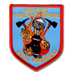 Ecusson brodé des pompiers de Crémieu. En forme de blason, l'écusson représente un pompier marchant dans les flammes avec un casque et devant deux piolets. le tout est sur fond bleu et il est écrit en jaune Amicale sapeurs pompiers Isle cremieu. Le bord de l'écusson est rouge.