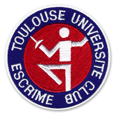 Ecusson du club d'escrime du TUC. Il représente, au centre, une personne faisant de l'escrime, brodée en blanc sur fond rouge. Autour, un bandeau bleu sur lequel il est écrit Toulouse Université club escrime.